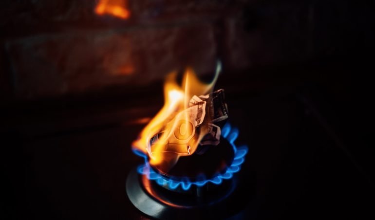 Energy crisis after Russias invasion of Ukraine. Increase the cost of supply, payment for natural gas. Paper banknote burns like fuel on gas stove burner in the kitchen.
