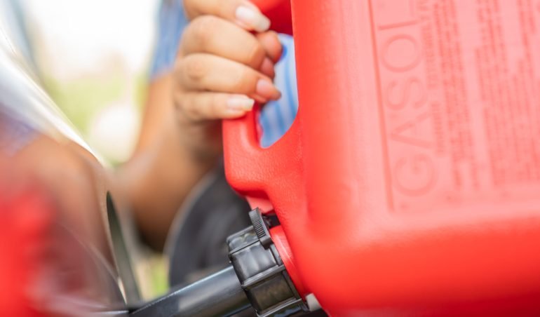 Lady filling her car with gasoline with a red gallon