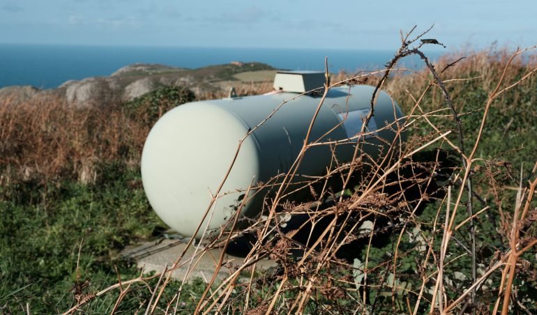 Propane storage tank in rural location with view of sea, Pembrokeshire, Wales.